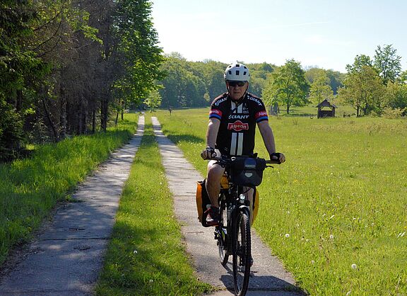 Person auf Rad mit Packtaschen durch Natur fahrend